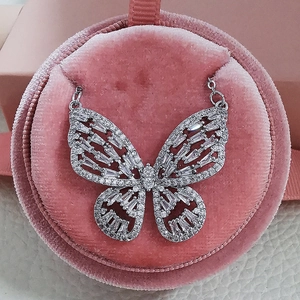 Macro shot of silver hollow butterfly pendant with white crystals in pink velvet box