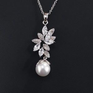 Macro shot of silver leaf pendant with sparkling zircon gems and round white pearl