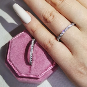 Close-up of sparkling pink eternity ring worn on finger next to a velvet jewelry box