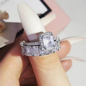 Primer plano de anillo de compromiso corte esmeralda y alianza de boda a juego