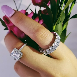 Primer plano de conjunto de anillos de circón talla esmeralda y banda baguette en mano