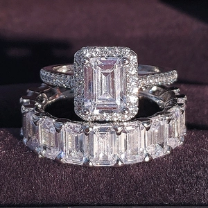 Set de anillos de circón corte esmeralda con halo de diamantes sobre terciopelo morado