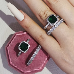 Dettaglio del set di anelli con smeraldo verde e alone di diamanti in metallo lucido