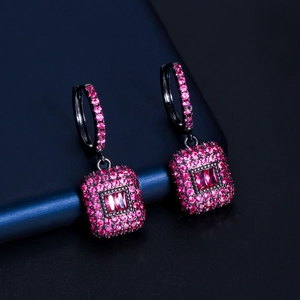 Dettaglio di orecchini in metallo nero con pietre di zircone rosa incastonate micro