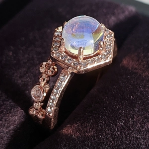 Roségouden maansteen ring met zeshoekig halo-ontwerp op een paars fluwelen juwelendoos