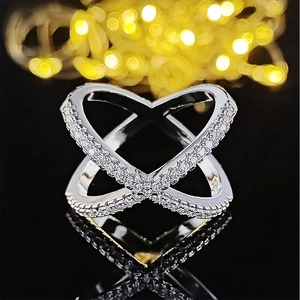 Chic silver crossover ring featuring pavé-set sparkling crystals on a black reflective base