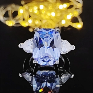 Elegant three-stone ring with blue emerald cut zircon and side pear shaped diamonds