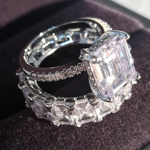 Luxe verlovingsring set met smaragd slijpvorm en eternity band op paars fluweel