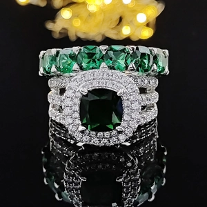 Ensemble de bijoux luxe argenté avec pierre précieuse vert foncé et bague halo sur fond noir