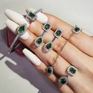 Luxury emerald jewelry set with silver necklace, earrings and ring on a hand