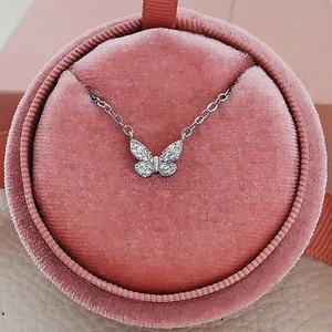 Collier papillon argenté étincelant avec zircons dans une boîte à bijoux en velours rose