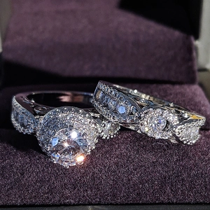 Primer plano de un set de anillos de lujo con halo redondo y banda de diamantes ondulada