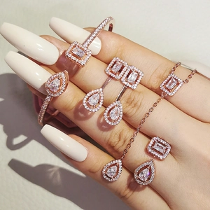 Luxurious rose gold jewelry set with rectangle and pear-shaped crystals on gray leather