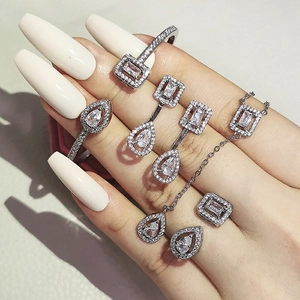 Detailed view of silver jewelry set with pear and emerald cut white zircon crystals