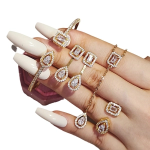 Luxury gold jewelry set featuring teardrop and rectangular white crystals worn on hand