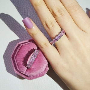 Detalle de anillo con piedras rosas de corte cuadrado y caja de joyas de terciopelo