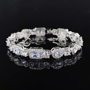 Detailed close-up of silver geometric bracelet with sparkling crystals on dark mirror surface
