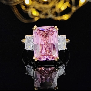 Detailed macro view of a pink emerald-cut gemstone ring on a dark reflective surface