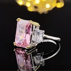 Macro shot of a large pink rectangle-cut gem set in a silver and gold ring with bokeh light