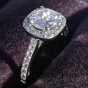 Macro de un anillo de compromiso de plata con piedra redonda y halo cuadrado