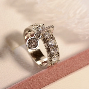 Macro detail of silver ring featuring five clear zircons and a champagne stone pendant