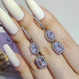 Luxury 925 silver drop earrings with oval and rectangular crystals held by a model