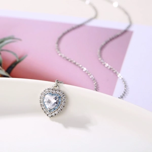 Makroaufnahme von Herzanhänger aus Silber mit blauen Steinen und Kristallen an feiner Kette