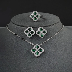 Nahaufnahme eines silbernen Kleeblatt-Schmucksets mit smaragdgrünen Steinen und Diamanten