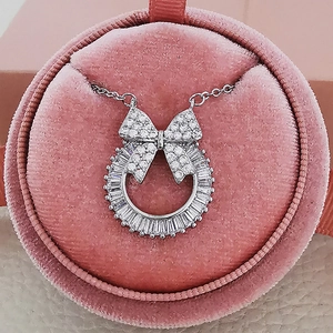 Silver bow wreath necklace with baguette-cut cubic zirconia in a pink velvet jewelry box