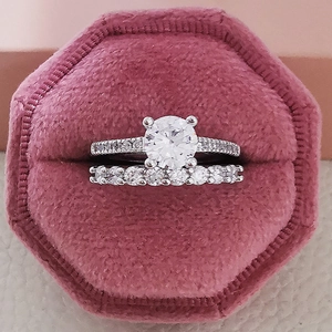 Vista macro de un set de anillos de boda plateados en una caja de terciopelo rosa