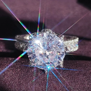 Elegante anillo de compromiso con gran solitario redondo y banda con pavé en terciopelo