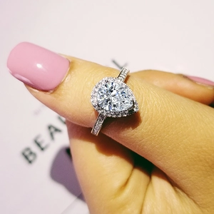 Detalle de anillo de diamante corte pera con engaste halo y banda de pavé