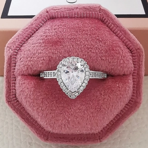 Primer plano de un anillo halo de pera en un joyero hexagonal de terciopelo rosa