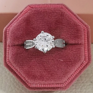 Primer plano de un anillo de plata con gran cristal redondo en caja de terciopelo rosa