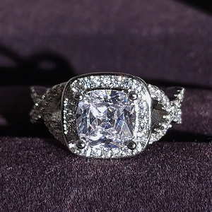 Dettaglio macro di anello con cristallo taglio cushion, design halo e fascia argento