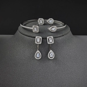 Elegantes silbernes Schmuckset mit Kristallarmband und Ohrhängern auf grauem Ständer