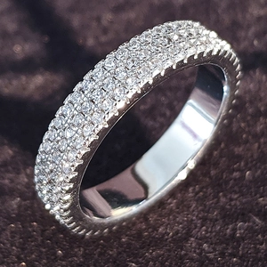 Primer plano macro de un anillo de eternidad en plata con tres filas de circonitas pavé