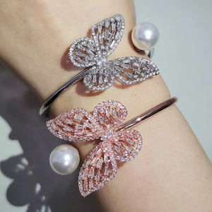 Detail of silver and rose gold irregular open bracelets with pavé butterfly and pearl