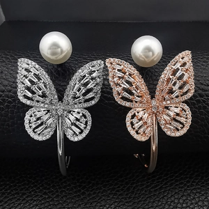 Macro detail of butterfly ring with hollow zircon wings and a white pearl on black leather