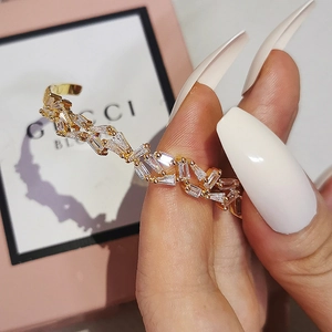 Close-up of a gold adjustable irregular cuff bracelet with baguette-cut zircon stones