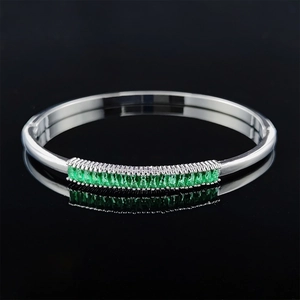 Detailed view of irregular silver open bracelet with emerald green rectangular gemstones