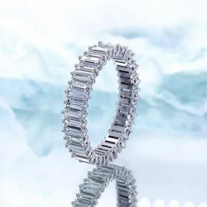 Anello eternity con pietre taglio baguette in oro bianco su sfondo di seta blu specchiata