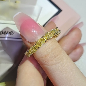 Detailed close-up of yellow gemstone eternity ring on a hand with pink nails