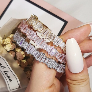 Detail of three-tone stackable rings with baguette-cut zircons in gold, silver and rose gold