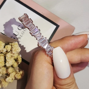 Detailed view of irregular rose gold ring with baguette-cut gemstones on hand