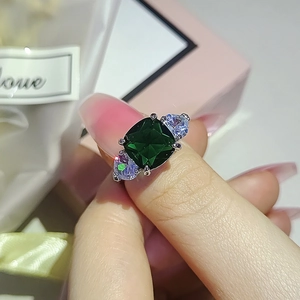 Classic silver emerald cut ring with pear side stones shown on finger with pink gift box