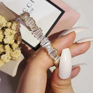 Detailed view of baguette cut clear crystals set in a golden irregular open cuff bracelet
