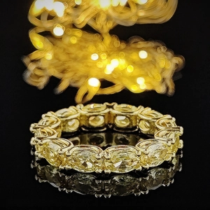 Eternity ring with oval yellow gemstones in golden claw setting and luxurious bokeh background