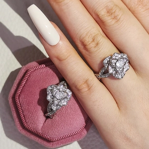 Detalle de anillo de camelia plateado con circonitas sobre un joyero de terciopelo rosa