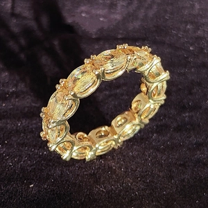 Golden eternity ring with oval-cut yellow gemstones in a claw setting on black background